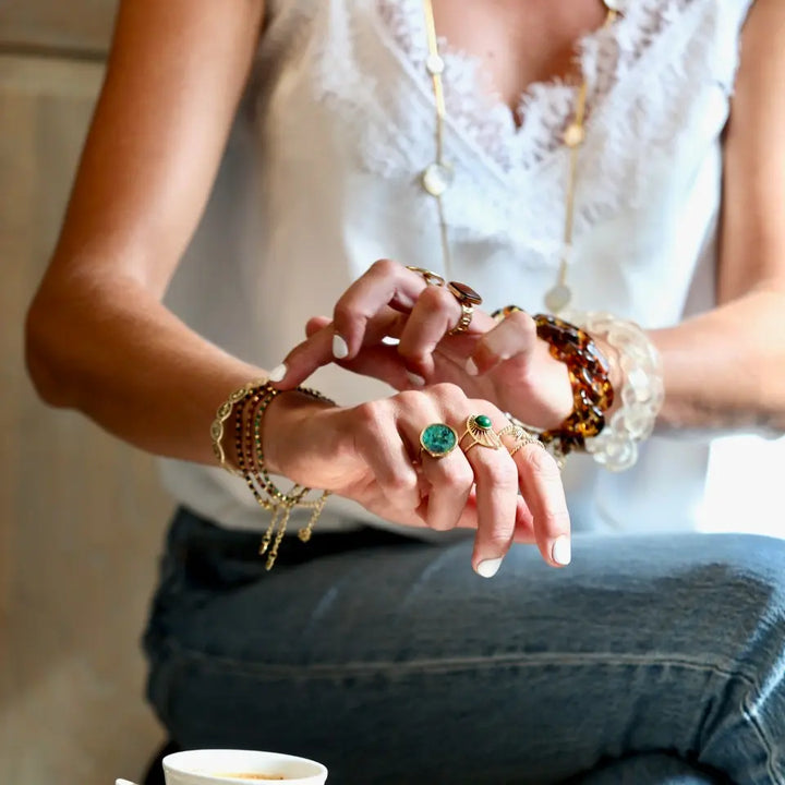 Bracelet grosse maille en plastique porté au poignet en accumulation avec des bijoux en acier inoxydable