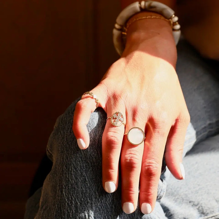 Bague Madone en acier inoxydable doré composée d'un anneau ovale avec une croix ornée de strass blancs portée au doigt 2