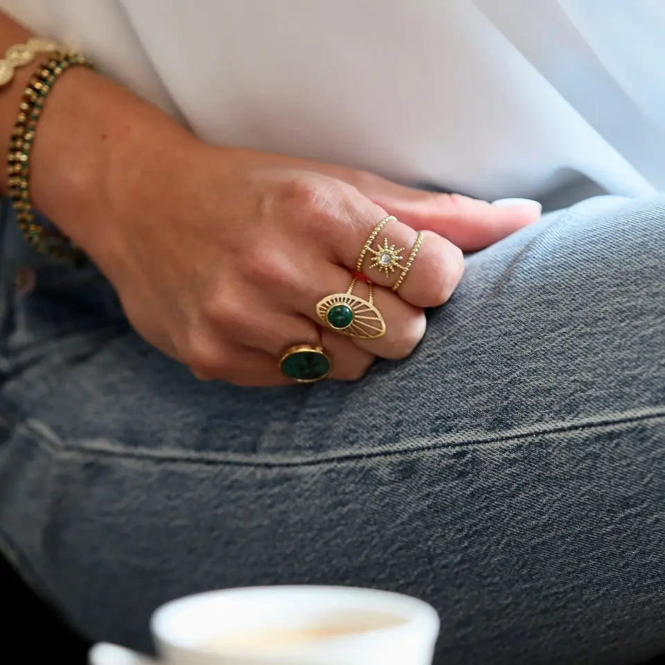 Bague ajustable en acier inoxydable composée d'un soleil orné d'un strass portée au doigt