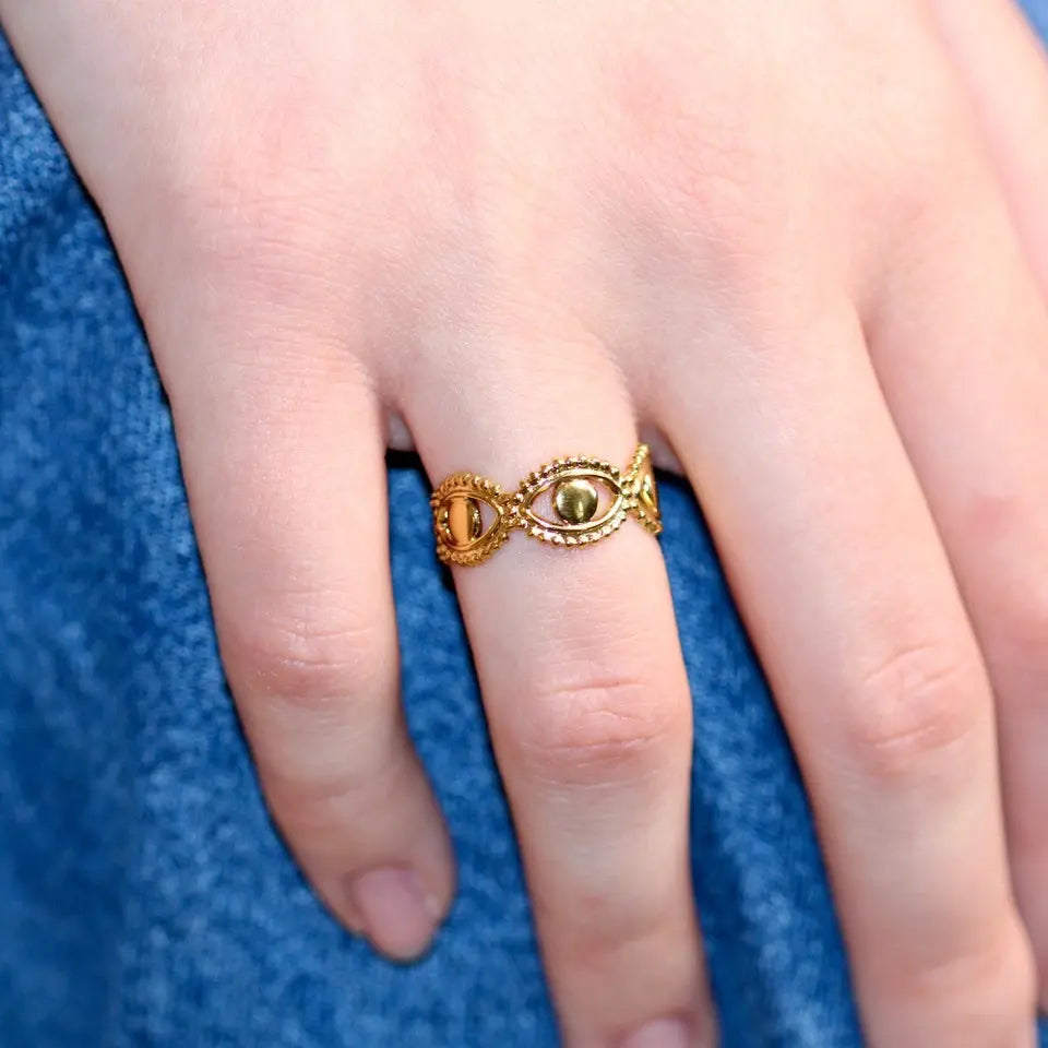 Bague ajustable en acier inoxydable doré composée d'un motif en forme d’œil accolé portée aux doigts