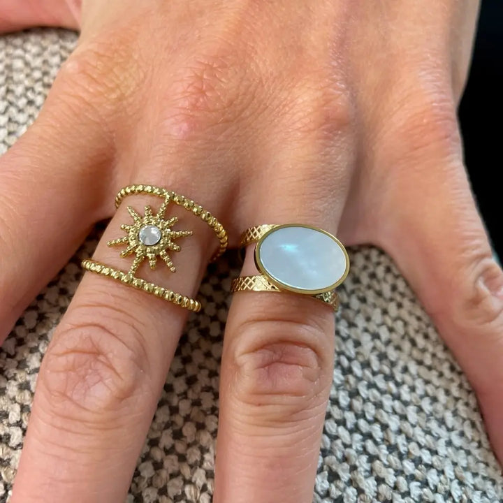 Bague ciselée en acier inoxydable orné d’une pièce ovale sertie d’une nacre blanche portée au doigt en accumulation