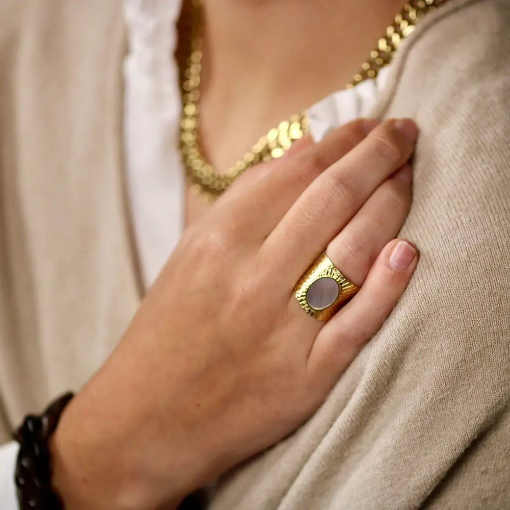 Bague large en acier inoxydable doré ornée d'une pièce ovale sertie d'une nacre portée au doigt