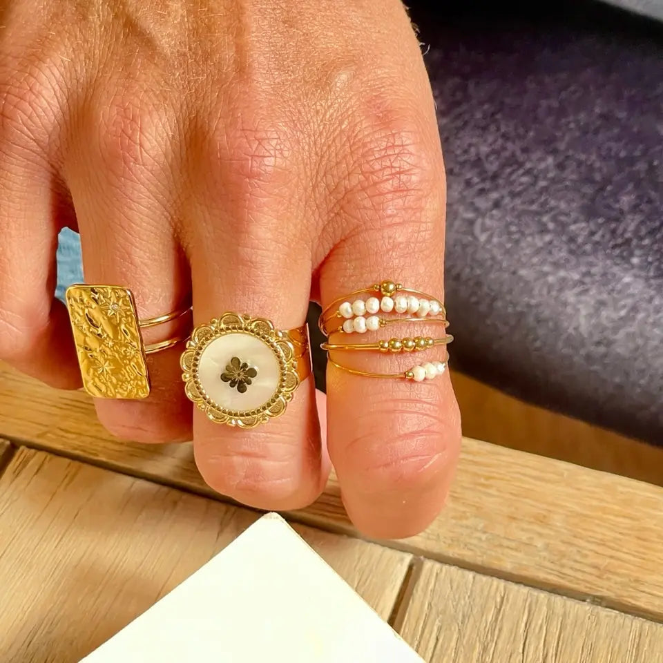 Bague multi anneaux en acier inoxydable composée de 5 rangs sertis de petites perles d'eau douce portée au doigt en accumulation