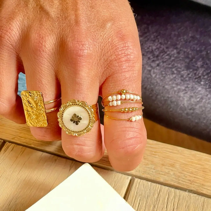 Bague multi anneaux en acier inoxydable composée de 5 rangs sertis de petites perles d'eau douce portée au doigt en accumulation