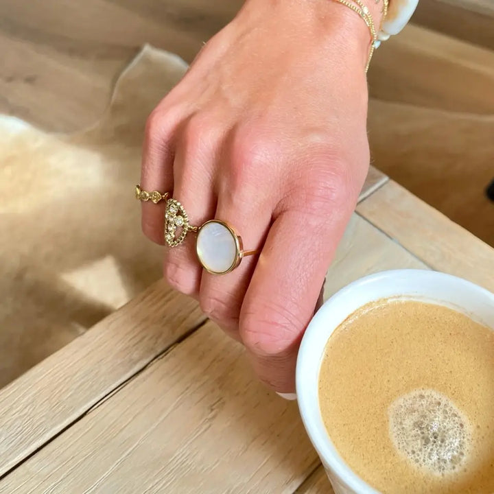 Bague pierre ronde en acier inoxydable doré ornée d'une pièce ronde sertie d'une nacre portée au doigt