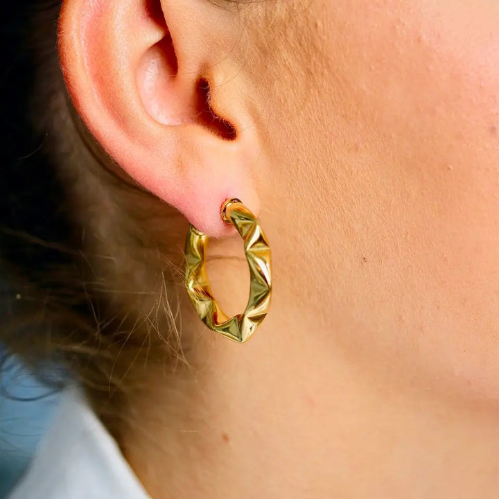 Boucles d’oreilles anneaux structurées en acier inoxydable doré portées aux oreilles