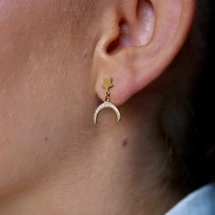 Boucles d'oreilles demi lune en acier inoxydable doré avec une pièce pendante au motif de lune strassée portées aux oreilles