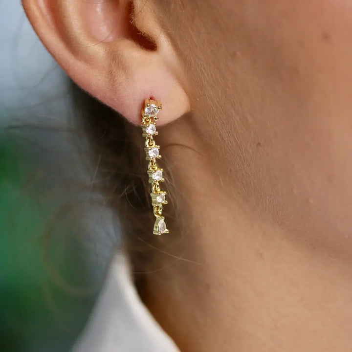 Boucles d’oreilles longues strass en acier inoxydable composées de six strass vert portées aux oreilles