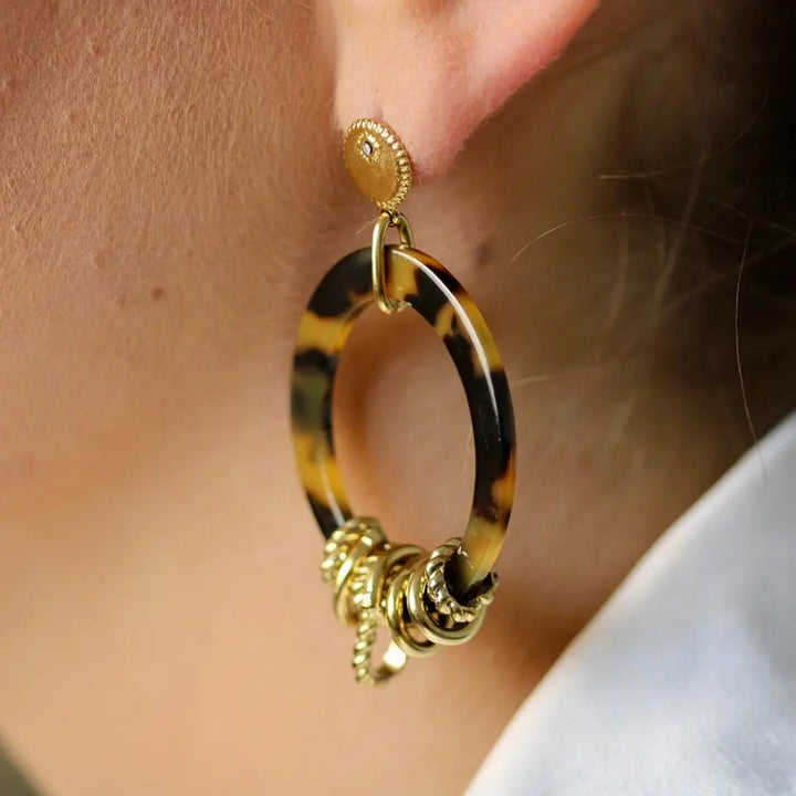 Boucles d’oreilles ovales en résine léopard et acier inoxydable doré portées aux oreilles