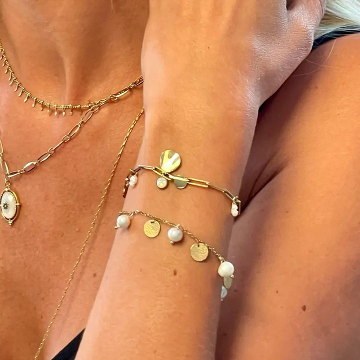 Bracelet à maillons en acier inoxydable doré avec perles d’eau douce, pierre white opale et pampilles ondulée porté au poignet