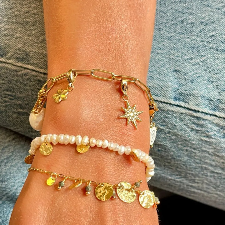 Bracelet CHARMS à maillon en acier inoxydable doré avec pampilles perle d’eau douce, étoile, fleur et soleil porté au poignet