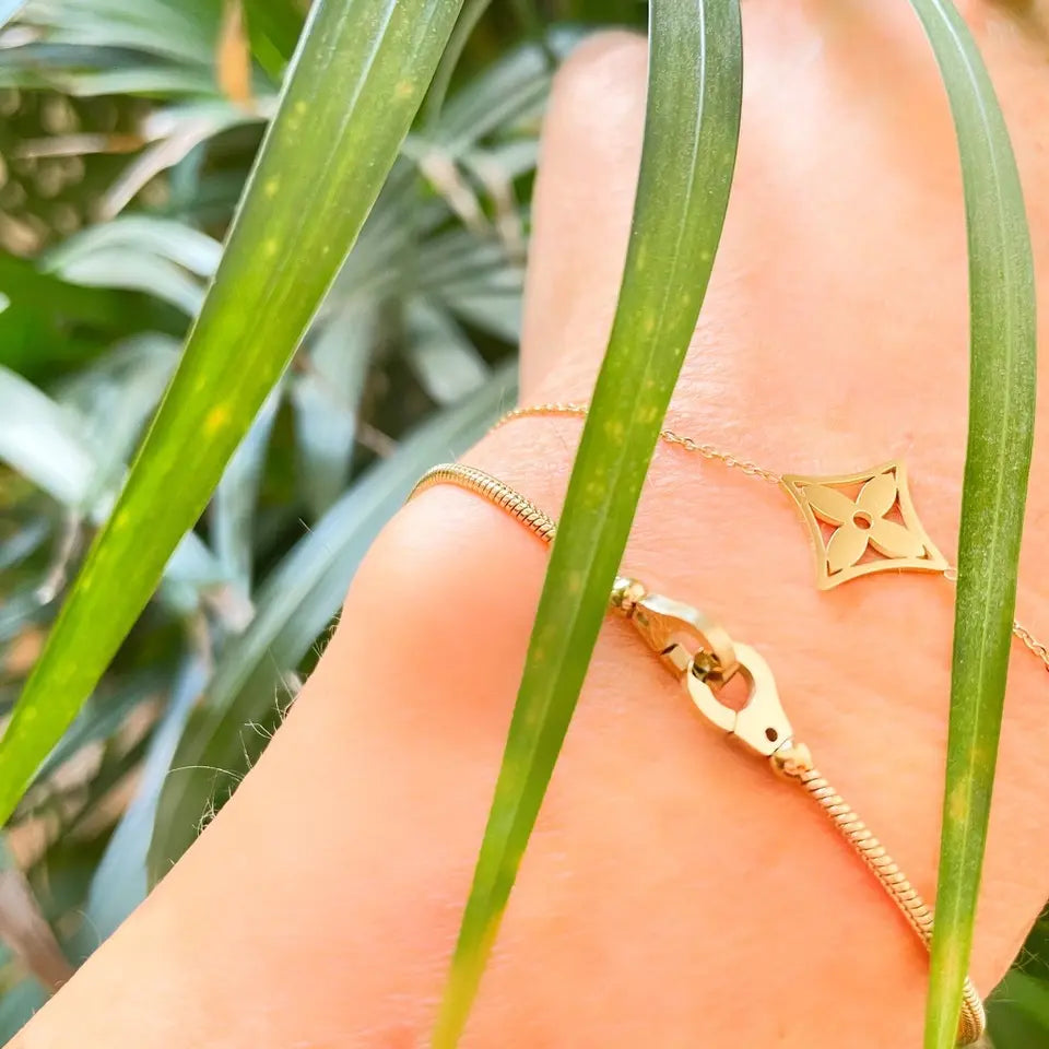 Bracelet fin en acier inoxydable doré avec un médaillon en forme de fleur porté au poignet