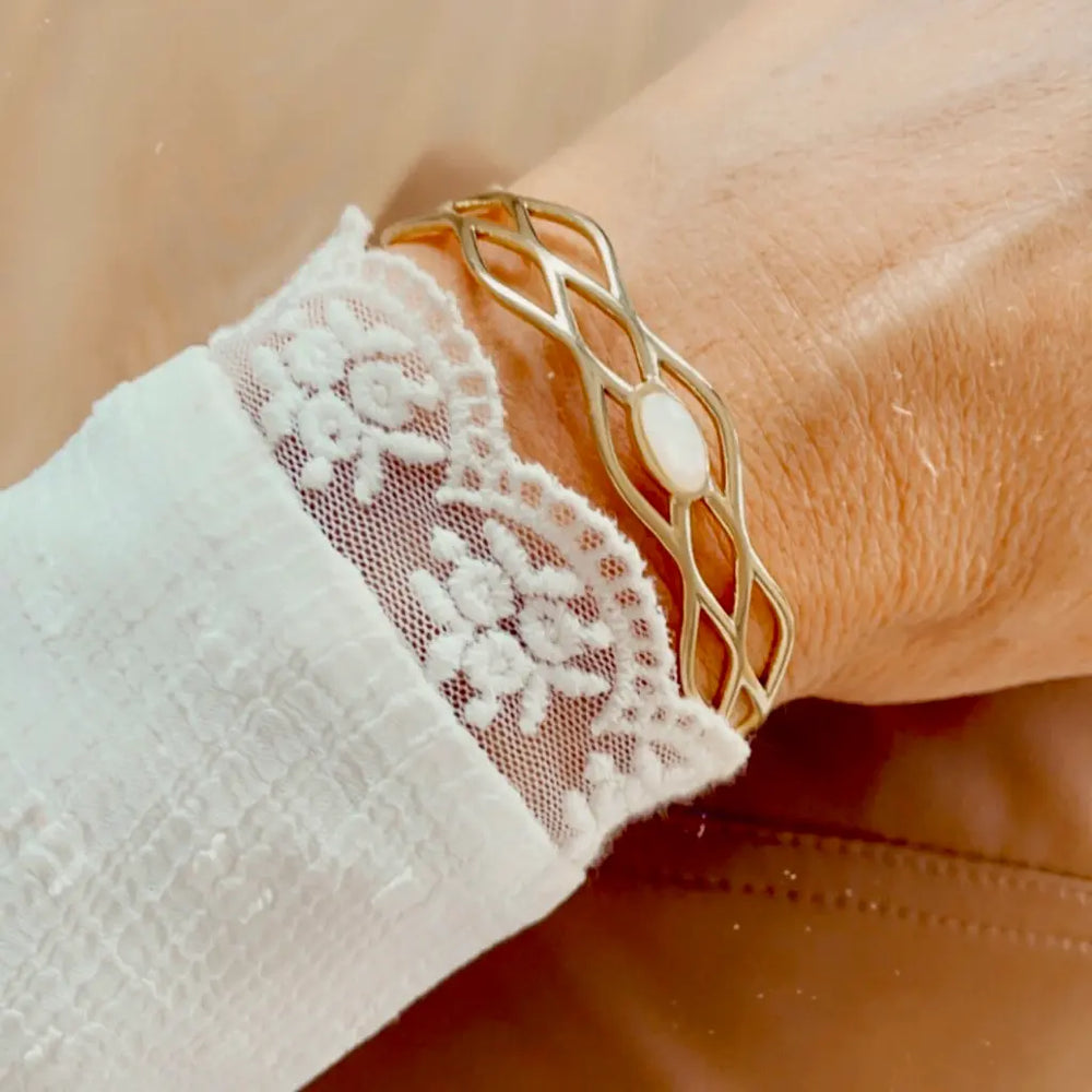 Bracelet jonc ajouré en acier inoxydable ajustable aux motifs géométriques orné d'une nacre porté au poignet