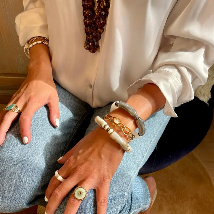Bracelet jonc ajouré en acier inoxydable ajustable aux motifs géométriques orné d'une nacre porté au poignet en accumulation
