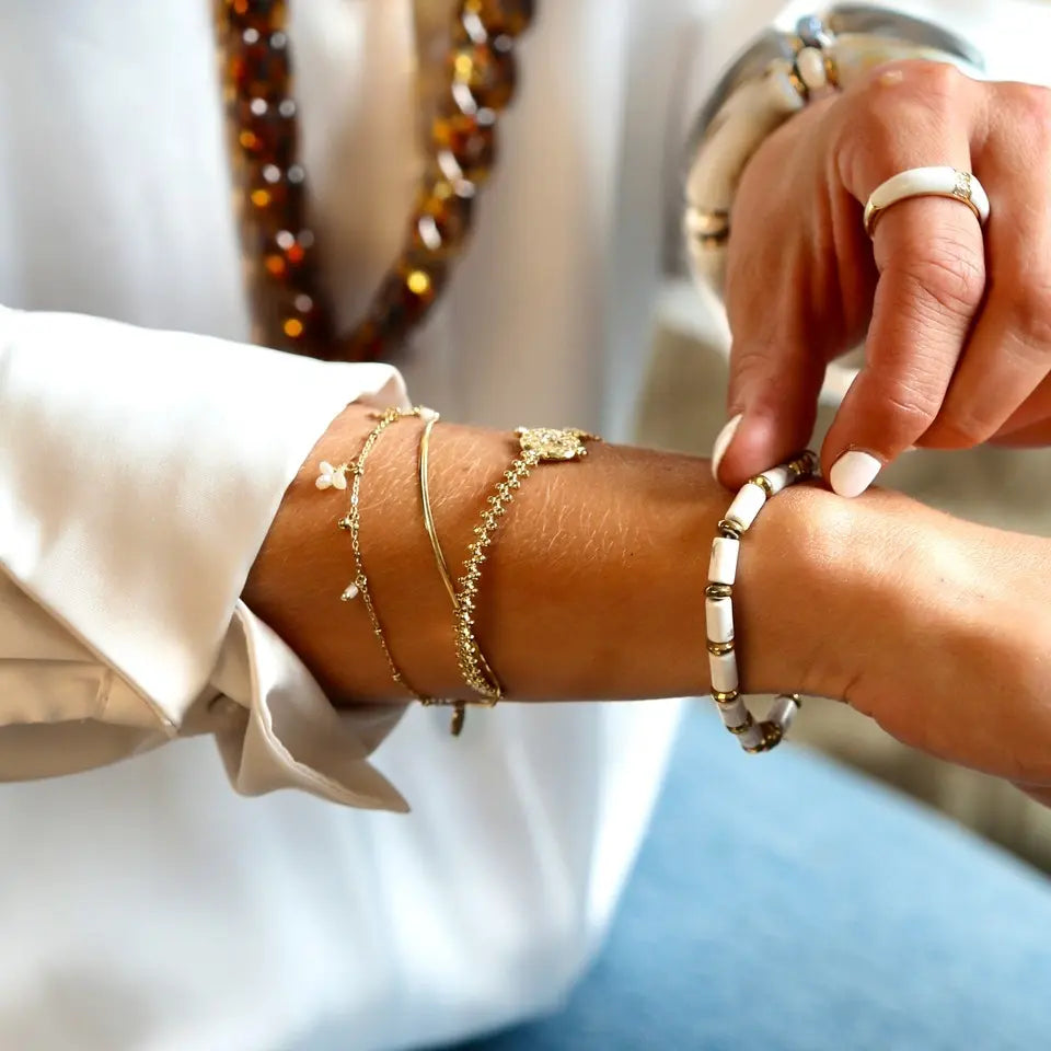 Bracelet jonc croix ajustable en acier inoxydable doré ornée de strass porté au poignet en accumulation