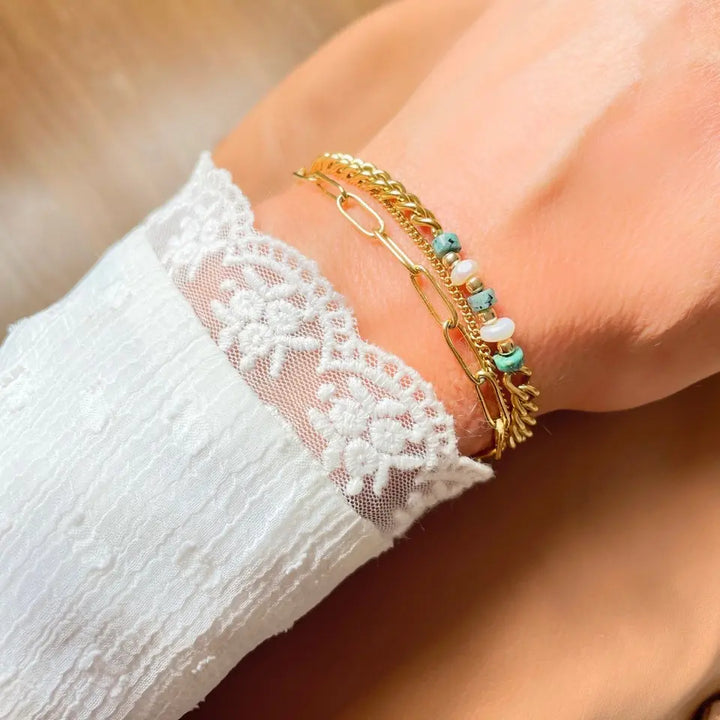 Bracelet 3 rangs composé d'une chaine à maillon, d’une chaine en maille fine et d’une chaine en maille gourmette avec des pierres turquoise africaine et des perles d’eau douce porté au poignet