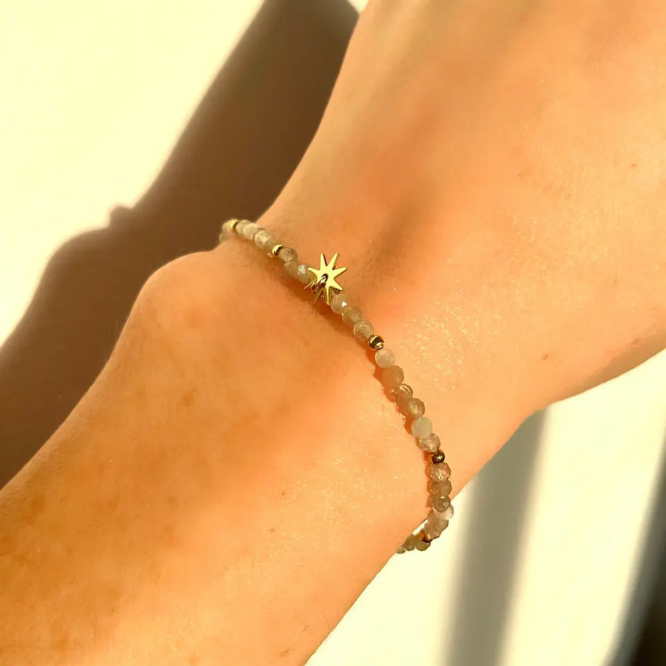 Bracelet en pierres labradorite et perles d’acier inoxydable avec un médaillon en forme d’étincelle porté au poignet
