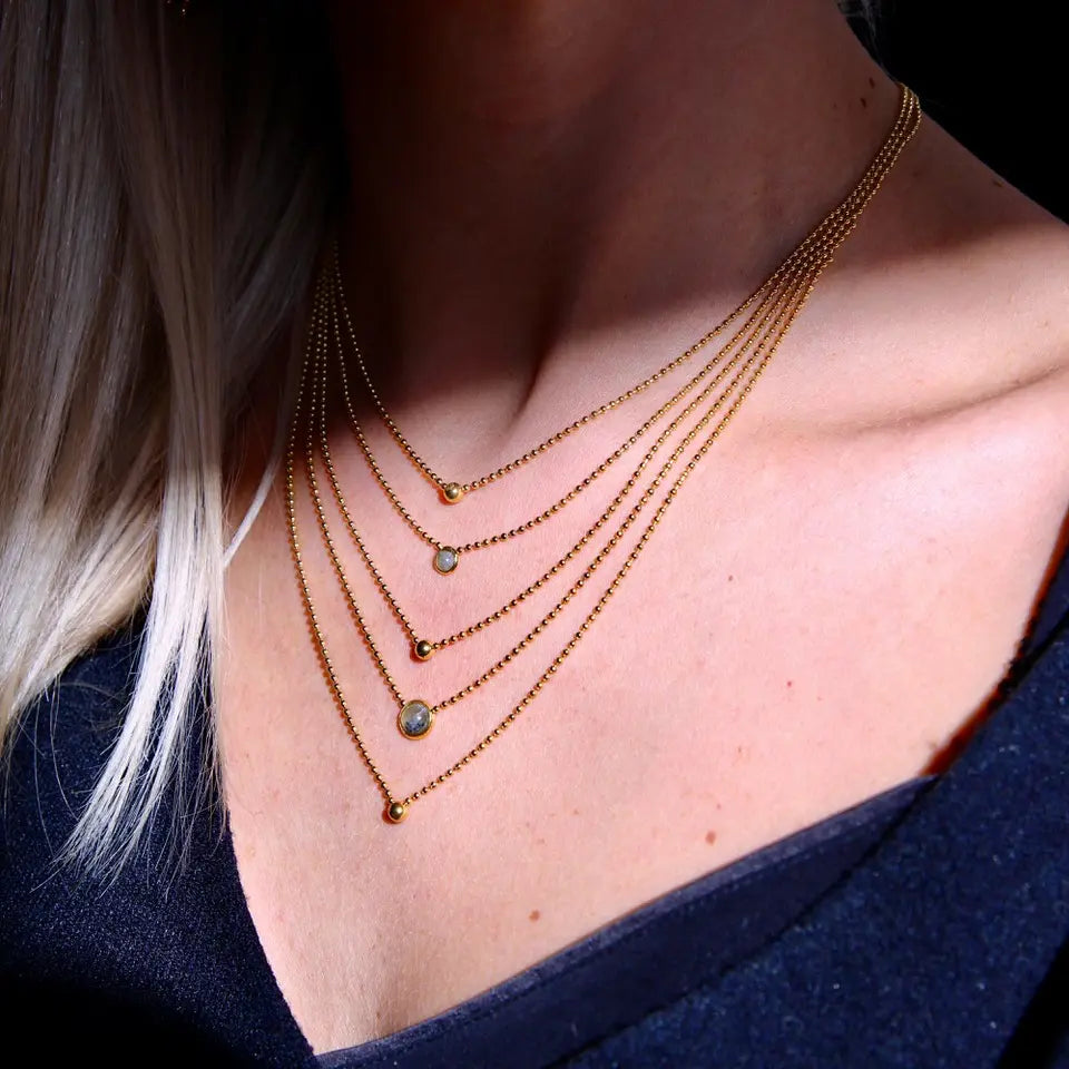 Collier cinq rangs composé de trois billes en acier inoxydable dorées et de deux pierres naturelles Labradorite porté au cou