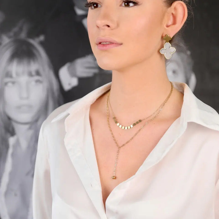Collier double rang en acier inoxydable doré composé d’une chaine à maille avec un pendant en forme de boule et d’une chaine maille fine ornée de sequins porté au cou