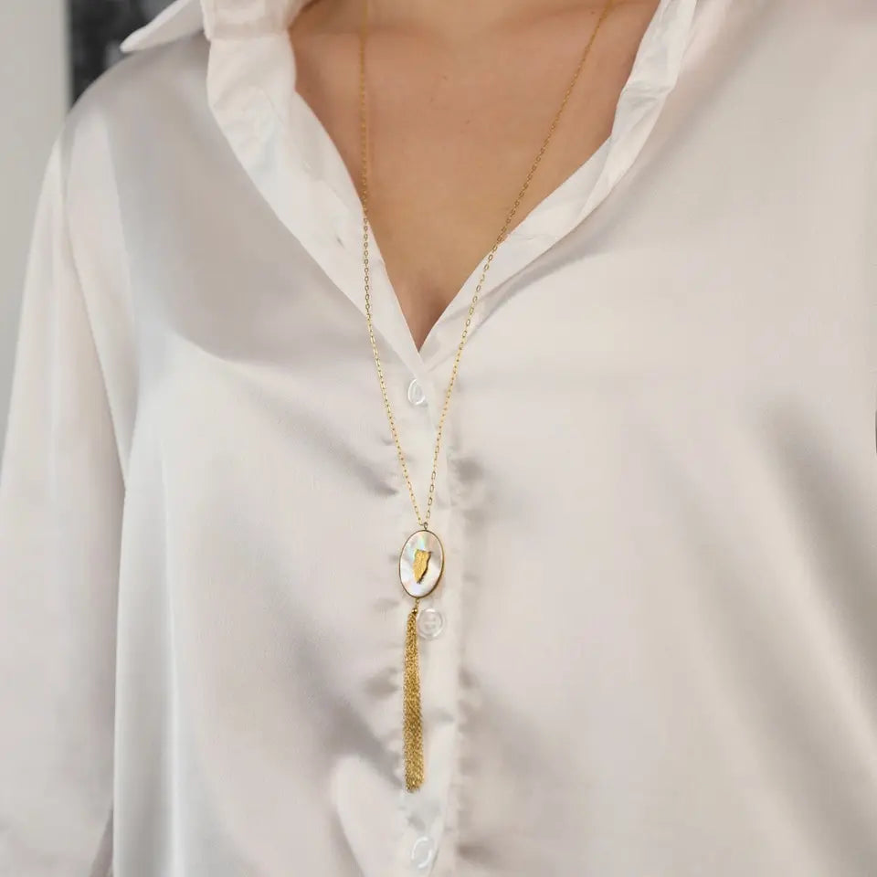 Collier sautoir hibou en acier inoxydable doré comprenant un pendentif ovale à frange serti de nacre et orné d’un motif représentant un hibou porté au cou